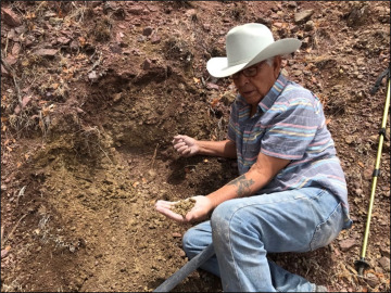 Juan Quezada wearing cowboy hat and holding soil sample