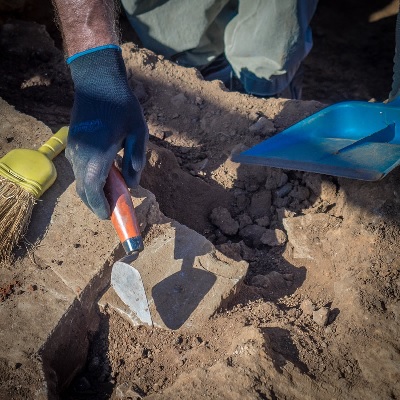 hand holding shovel excavating ancient building foundation