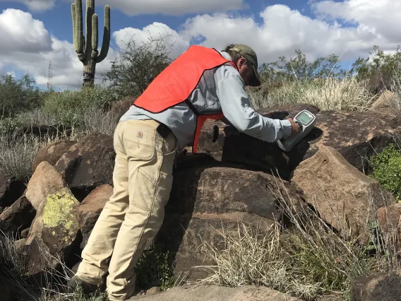 man looking over rocks in desert lanscape