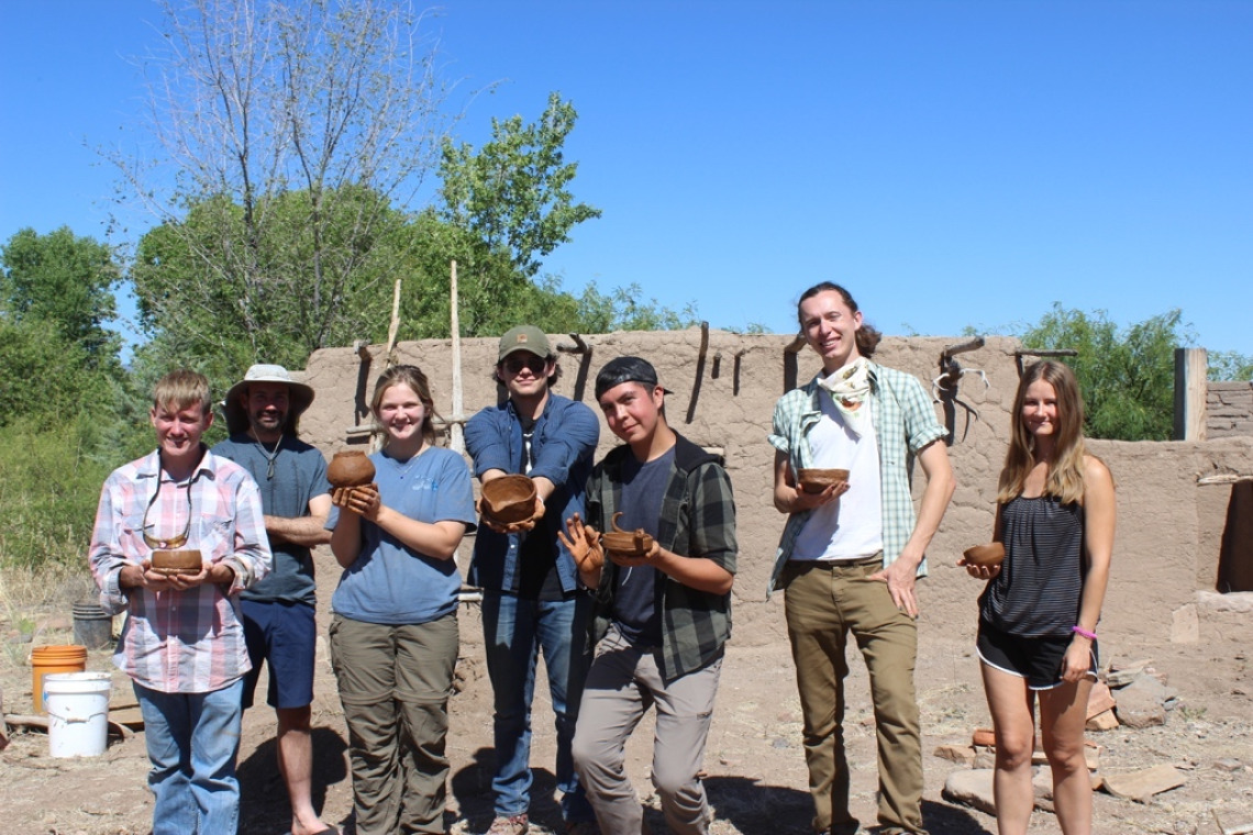Seven field school participants holding pots they made