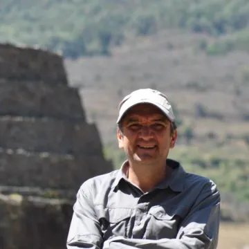 Man in ball cap in front of pre-Columbian pyramid