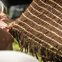 hand holding a corner of a woven object