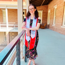 Kelly Smith on Old Main porch in academic regalia