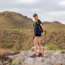 Mary with walking staff in front of small desert mountain