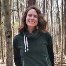Sarah Renkert in green hoodie in front of trees