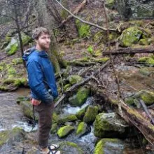 Skylar Benedict stand on a rock in a stream