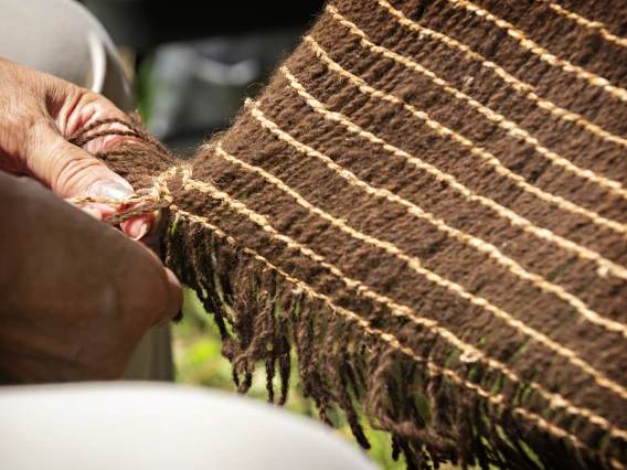 hand holding a corner of a woven object